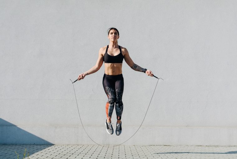 Young woman skipping ropes outdoors