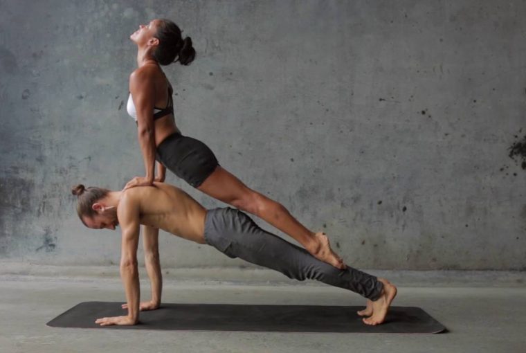 man and woman balancing on each other while practicing yoga