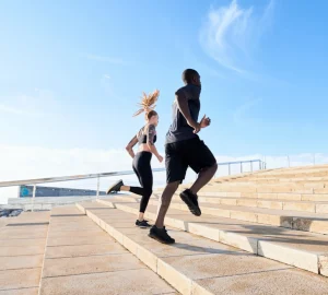 a couple running stairs at the beach