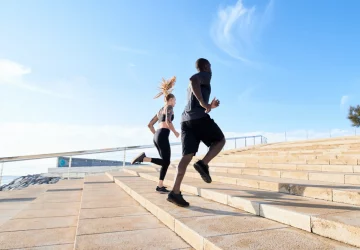 a couple running stairs at the beach