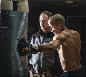 a muscular bald man hitting a punching bag