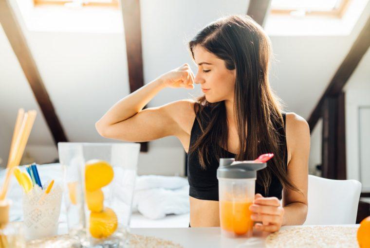 a woman flexing while drinking a healthy meal