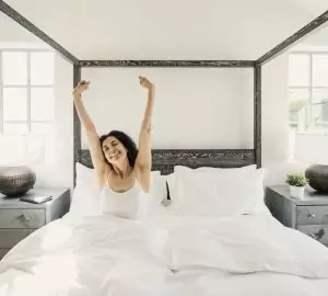 a woman stretching in her bed when she wakes up in the morning