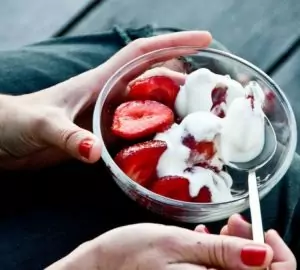 a person eating a bowl of strawberries and yogurt