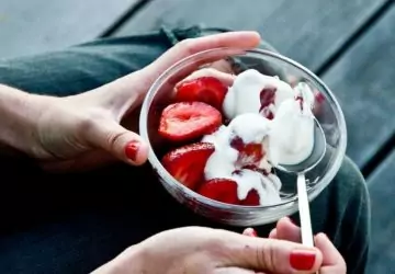 a person eating a bowl of strawberries and yogurt
