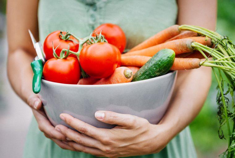 a woman holding a bowl of delicious vegetables